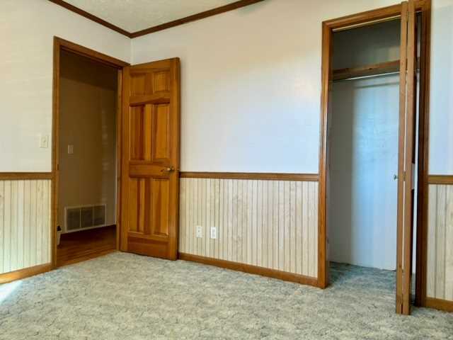 unfurnished bedroom featuring ornamental molding, a closet, and light carpet