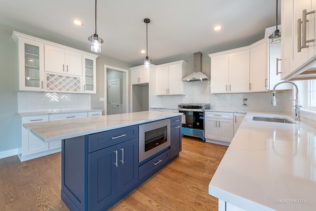 kitchen featuring hardwood / wood-style floors, backsplash, stainless steel appliances, sink, and wall chimney range hood