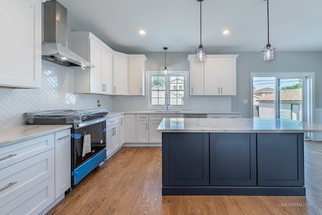 kitchen featuring light hardwood / wood-style flooring, stove, wall chimney exhaust hood, and tasteful backsplash