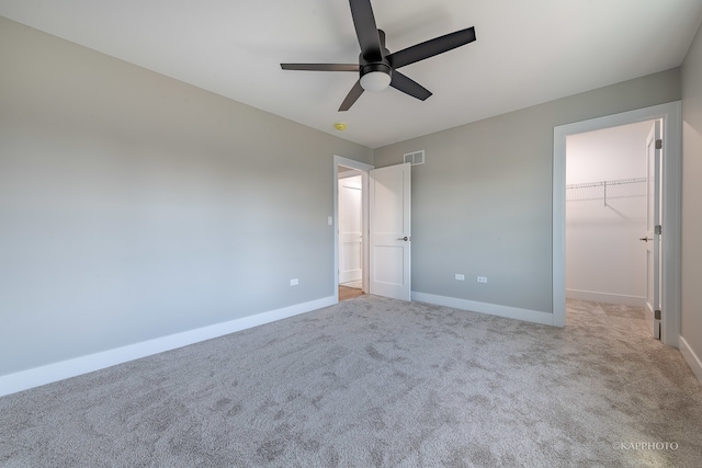 unfurnished bedroom featuring light colored carpet, a spacious closet, ceiling fan, and a closet