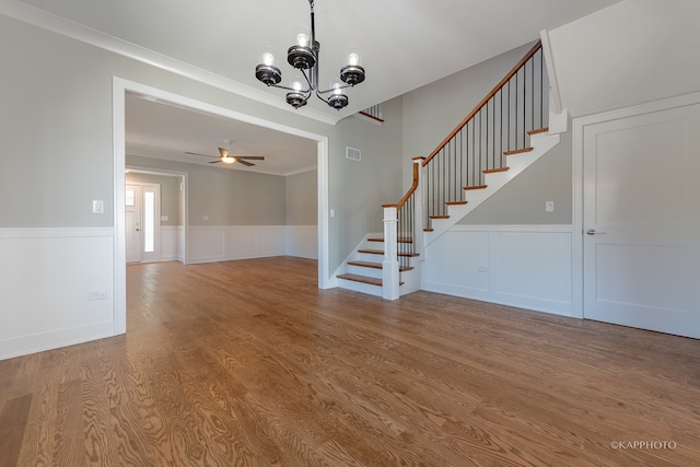 foyer with ornamental molding, ceiling fan with notable chandelier, and light wood-type flooring