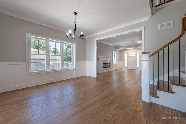 interior space with ornamental molding, a tiled fireplace, hardwood / wood-style floors, and ceiling fan with notable chandelier