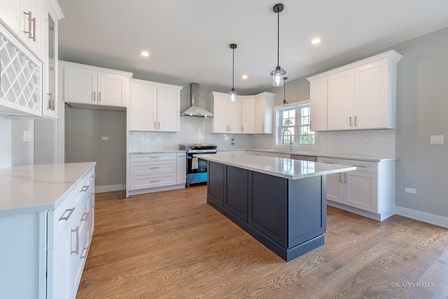 kitchen featuring a center island, wall chimney exhaust hood, stove, and light hardwood / wood-style floors