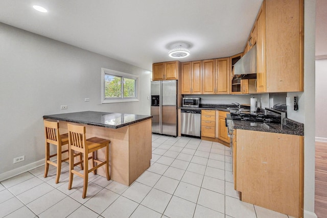 kitchen with wall chimney exhaust hood, stainless steel appliances, dark stone counters, and a breakfast bar