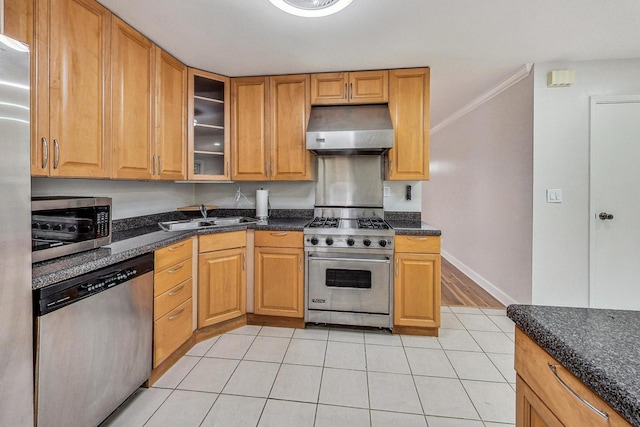 kitchen featuring light hardwood / wood-style floors, stainless steel appliances, ornamental molding, sink, and dark stone countertops