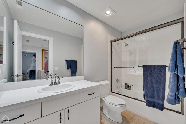 full bathroom featuring shower / bath combination with glass door, toilet, and vanity