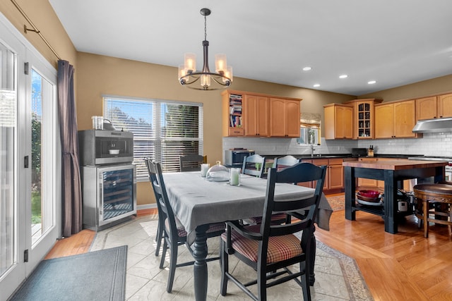 dining area featuring plenty of natural light, sink, wine cooler, and an inviting chandelier