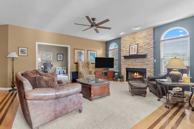 carpeted living room with plenty of natural light, a stone fireplace, and ceiling fan