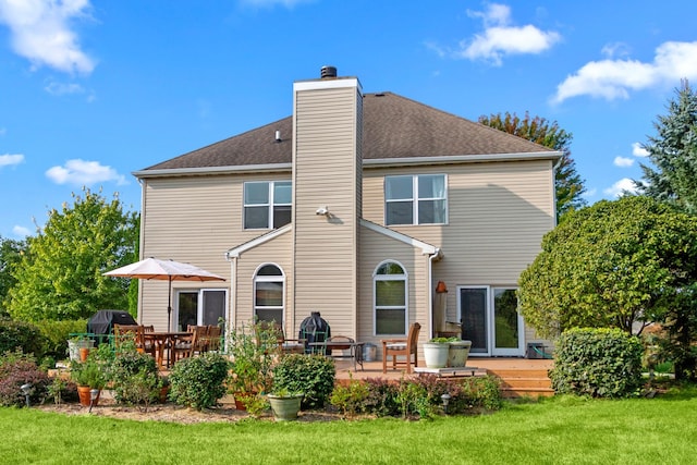 back of house with a wooden deck, a patio, and a lawn