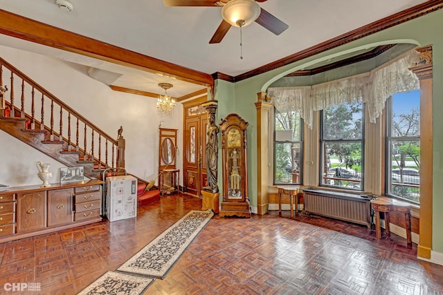 foyer with radiator heating unit, crown molding, ceiling fan with notable chandelier, and dark parquet flooring