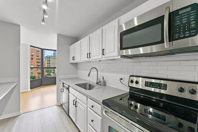 kitchen with white cabinetry, rail lighting, light hardwood / wood-style flooring, sink, and appliances with stainless steel finishes