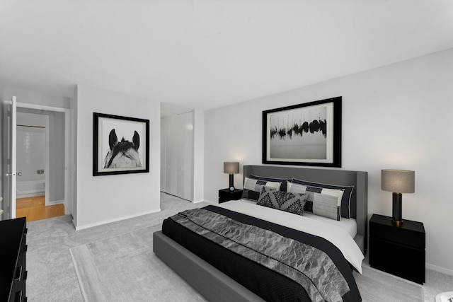 bedroom with ensuite bathroom and light hardwood / wood-style floors