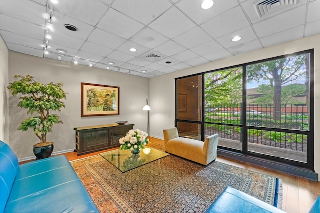 living room with track lighting, hardwood / wood-style flooring, and a drop ceiling