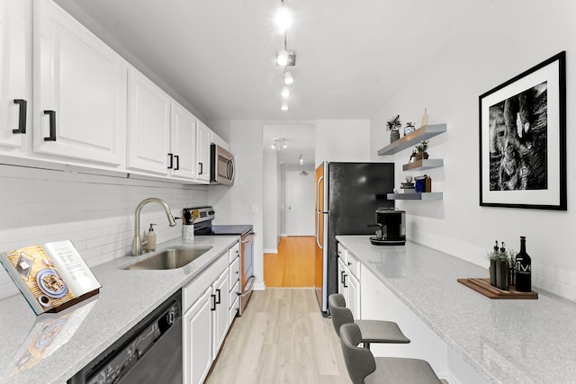 kitchen featuring light wood-type flooring, white cabinetry, rail lighting, black appliances, and sink