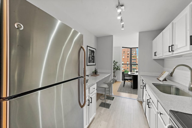 kitchen featuring light hardwood / wood-style floors, stainless steel refrigerator, sink, rail lighting, and decorative backsplash