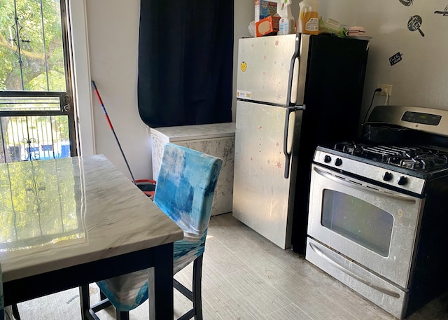 kitchen with plenty of natural light, light hardwood / wood-style flooring, and white appliances