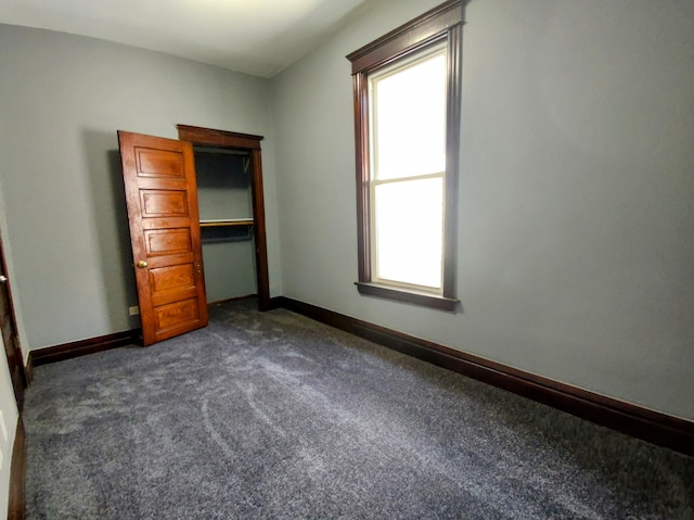 unfurnished bedroom featuring a closet and dark colored carpet