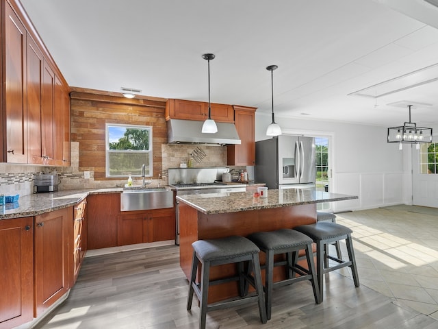 kitchen featuring stainless steel fridge with ice dispenser, tasteful backsplash, a center island, sink, and light wood-type flooring