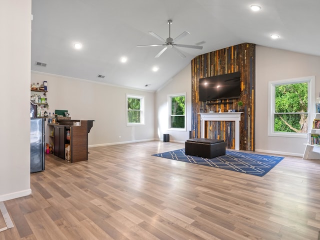 living room featuring a wealth of natural light, ceiling fan, light wood-type flooring, and a fireplace