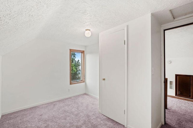 unfurnished bedroom featuring light carpet, a textured ceiling, and lofted ceiling