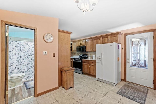 kitchen featuring an inviting chandelier, gas range, light hardwood / wood-style floors, decorative backsplash, and white fridge with ice dispenser