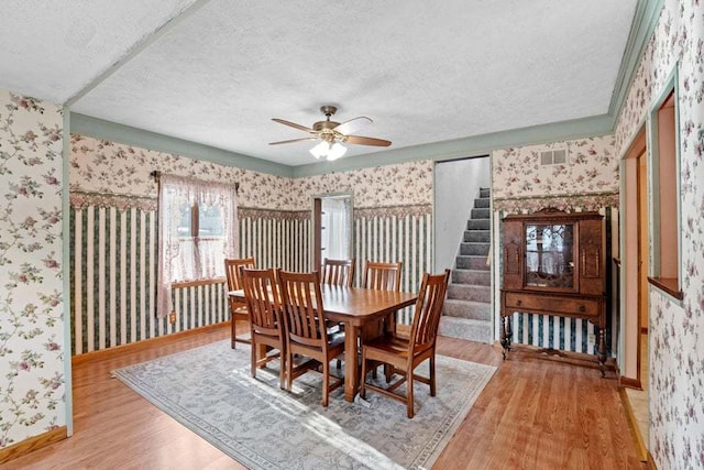 dining space featuring light wood-type flooring, ceiling fan, and a textured ceiling