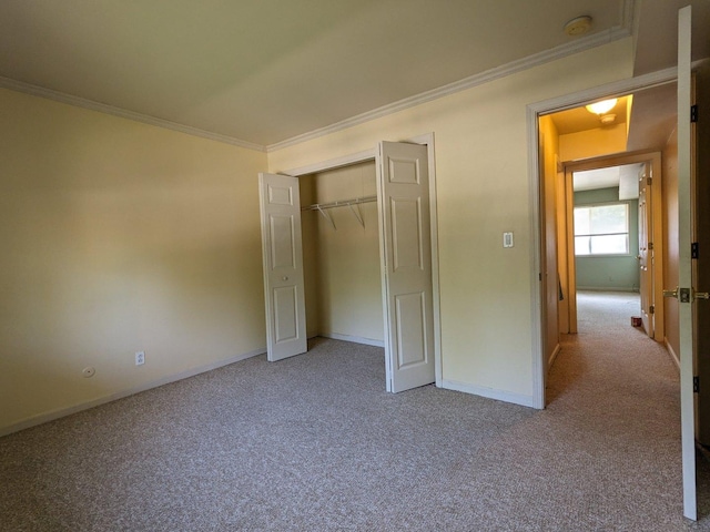 unfurnished bedroom featuring carpet floors, a closet, baseboards, and crown molding