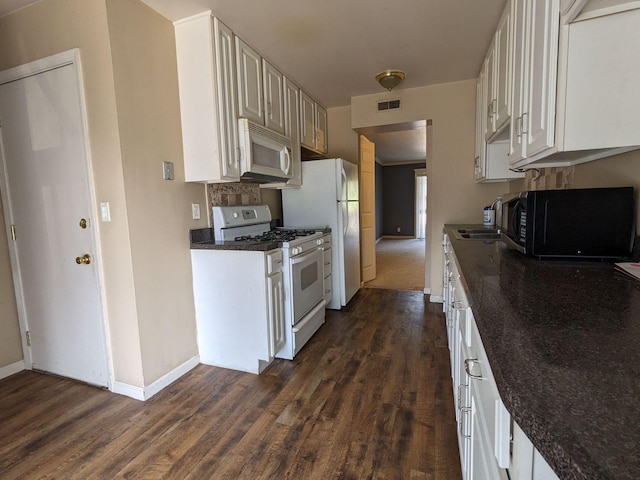 kitchen with white appliances, baseboards, visible vents, and dark wood-style flooring