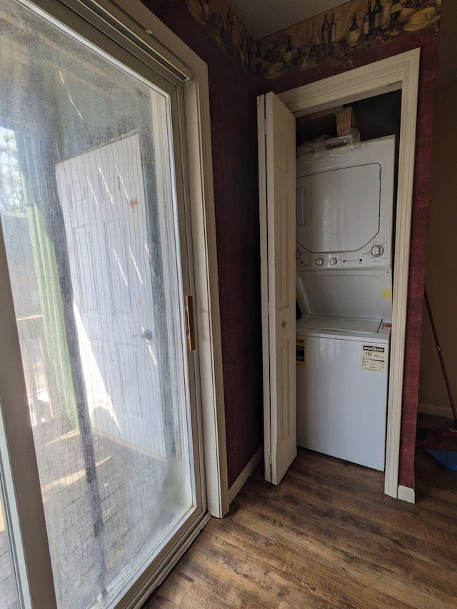 laundry room featuring stacked washer and dryer, dark wood-style floors, and laundry area