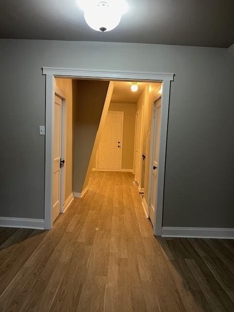 corridor with baseboards and wood finished floors