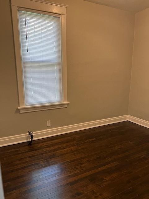 unfurnished room with dark wood-style floors and baseboards