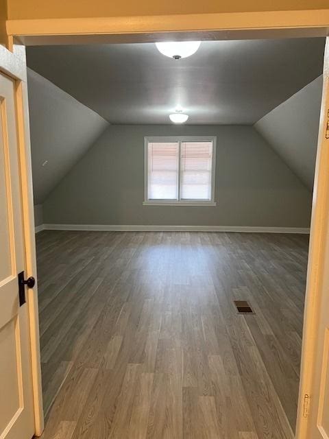 additional living space with wood finished floors, visible vents, and baseboards