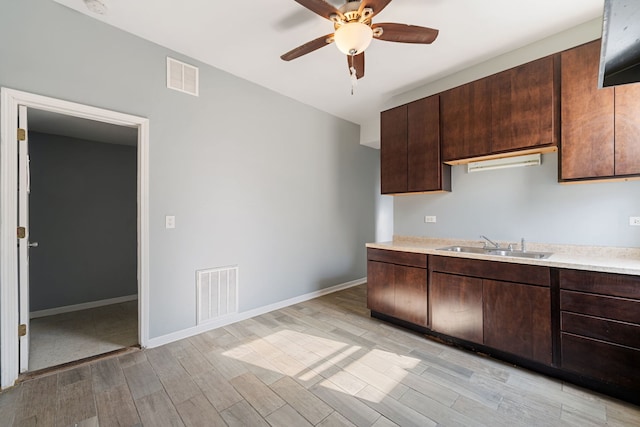 kitchen featuring ceiling fan, sink, dark brown cabinetry, and light wood-type flooring