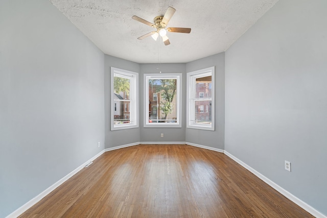 spare room with a textured ceiling, wood-type flooring, and ceiling fan