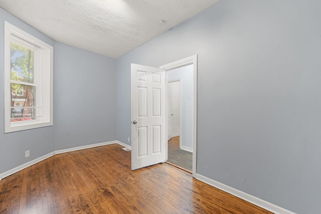 empty room with a textured ceiling and hardwood / wood-style flooring