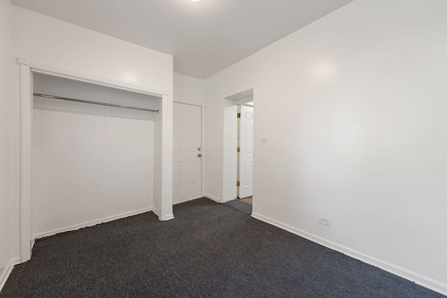 unfurnished bedroom with dark colored carpet and a closet