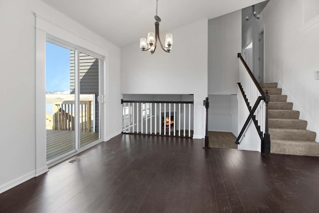 empty room with baseboards, visible vents, an inviting chandelier, and wood finished floors