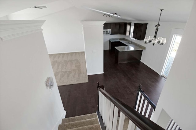 staircase featuring wood finished floors, rail lighting, baseboards, and an inviting chandelier