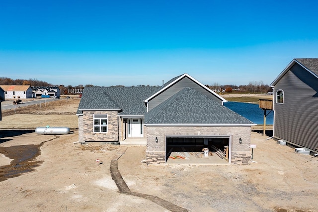 view of front of property with an attached garage, brick siding, and roof with shingles