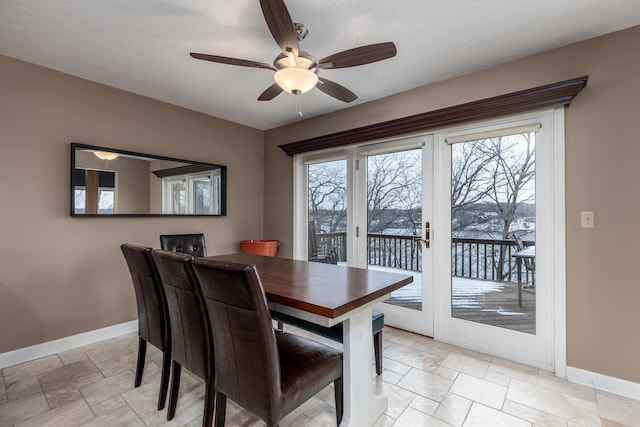 dining area with a ceiling fan, french doors, stone tile floors, and baseboards