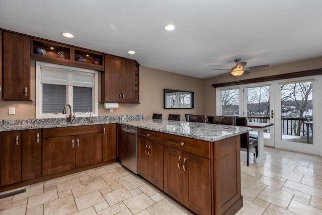 kitchen with stone tile flooring, visible vents, a sink, light stone countertops, and a peninsula