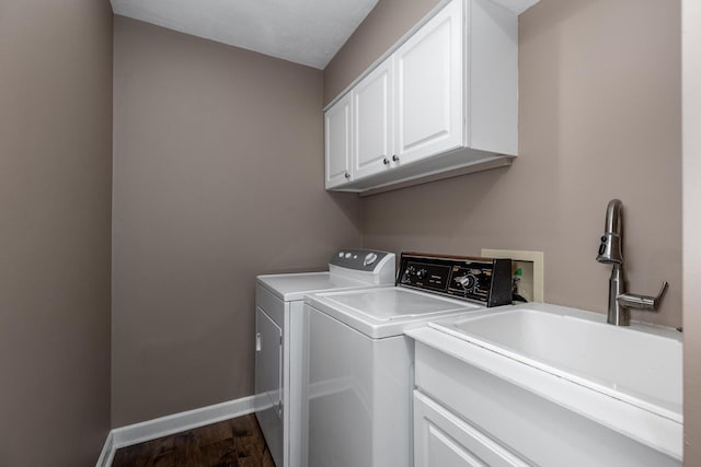 washroom featuring a sink, baseboards, washer and dryer, cabinet space, and dark wood-style floors