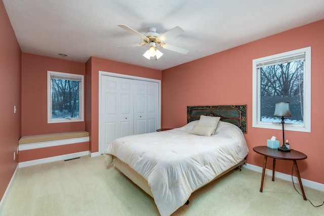 carpeted bedroom featuring a closet, visible vents, ceiling fan, and baseboards