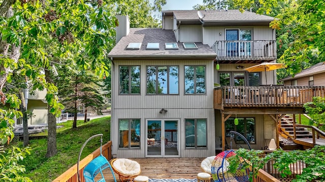 back of property with a chimney, a shingled roof, stairway, a balcony, and a deck