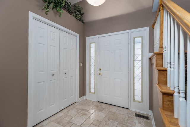 entrance foyer featuring stairway, visible vents, and baseboards