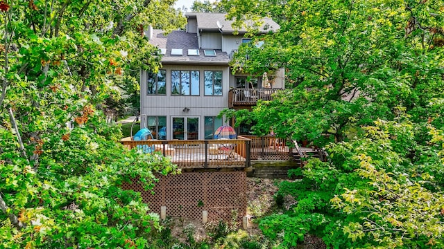 rear view of property with a shingled roof and a balcony