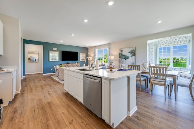 kitchen with light hardwood / wood-style flooring, white cabinetry, sink, an island with sink, and stainless steel dishwasher