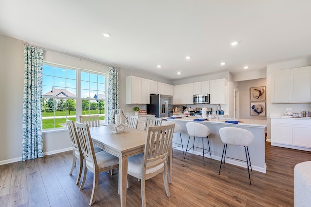 dining room with recessed lighting, baseboards, wood finished floors, and stacked washer and clothes dryer