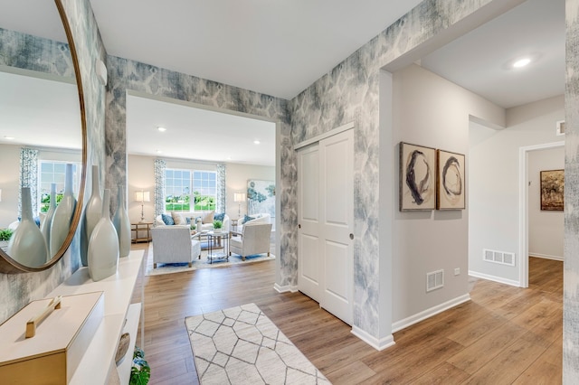 foyer entrance with light wood finished floors, baseboards, and visible vents