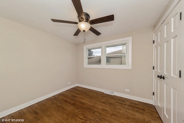 spare room featuring dark wood-type flooring and ceiling fan